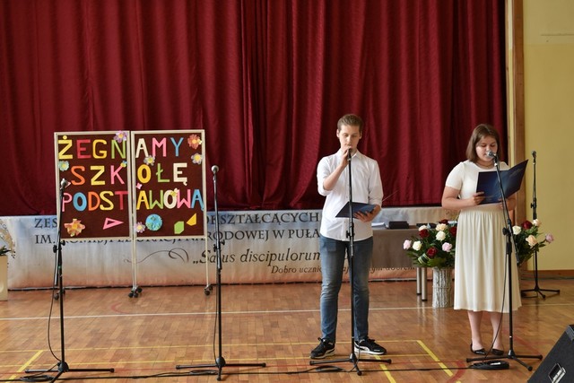 Zdjęcie przedstawiające uczennicę i ucznia stojących przed mikrofonem
